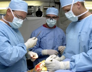 U.S. Air Force surgeons Dr. Patrick Miller (left), Dr. Michael Hughes (right), and surgical technician SrA Ray Wilson from the 379th Expeditionary Medical Squadron, repair the ruptured achilles tendon of a servicemember on March 11, 2003. The doctors are performing this surgey at a field hospital in a foward-deployed location. (U.S. Air Force photo by SSgt. DERRICK C. GOODE)(RELEASED)
